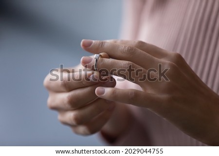 Unrecognizable young woman takes off wedding ring, remove engagement jewellery as sign of divorcement, close up cropped view. Break up, cheated wife, infidelity, marriage end, relations split concept Royalty-Free Stock Photo #2029044755