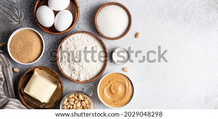 Ingredients for cooking peanut butter cookies top view. Culinary background. Place for text made of peanut butter, brown sugar, eggs, butter, baking powder, flour, peanuts and whisk. Copy space. Royalty-Free Stock Photo #2029048298