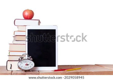 isolated stack of books with red apple digital tablet, alarm clock and colored pencils on the white background with copy space