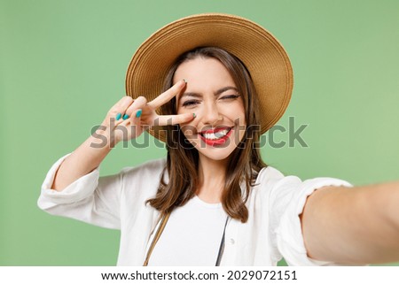 Close up traveler tourist woman in casual clothes hat camera do selfie shot on mobile phone v-sign gesture isolated on green background Passenger travel abroad on weekends Air flight journey concept