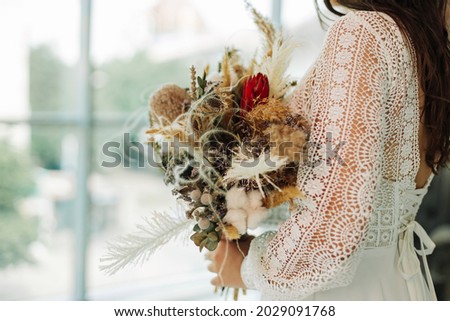 bride in a wedding dress holds a wedding bouquet of flowers and greenery in her hands, a Bride with a beautiful field bouquet close-up