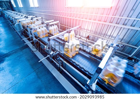 Modern strapping and transporting machine for packaging line at beverage plant.