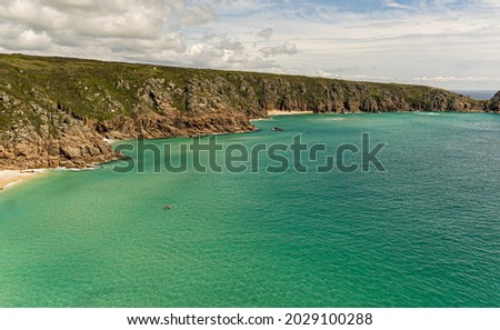 Photo of a couple kayaking in the turquoise waters of the Atlantic Ocean in a small cove in Cornwall, United Kingdom.
