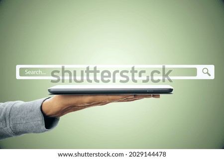 Businessman hand holding touchpad with creative website search bar hologram on gray background. Internet and browse concept