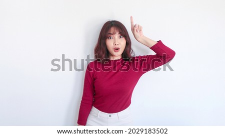 Shock Asian beautiful girl point above with red shirt in white background