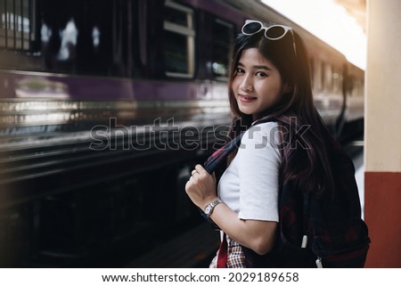 Image of a woman with a rucksack standing at a train station waiting to board a train. concept of solo travel.