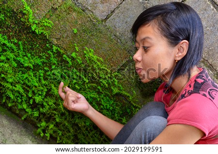 Freestyle photo of a girl behind a house with a concrete wall covered with moss