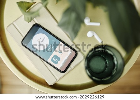 Top down view at smartphone with sleep assistant app on bedside table, copy space
