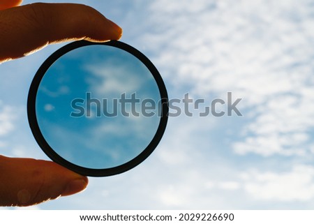 cpl polarization filter for photo video cameras in a man's hand against the background of the sky with clouds. effect of a polarizing filter. accessory for professional photographer videographer