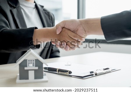 Business and brokers real estate agents shake hand after completing negotiations to buy houses insurance and sign contracts. Home insurance concept.