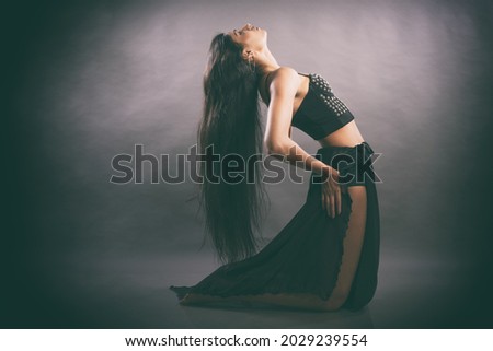 Indian young female performing aerobics dance poses in black costume