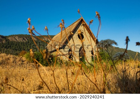 Old abandoned made of stone church isoleted in the field of countryside. Vancouver Island, BC, Canada. August 8,2021. Street view, travel photo, selective focus, blurred.