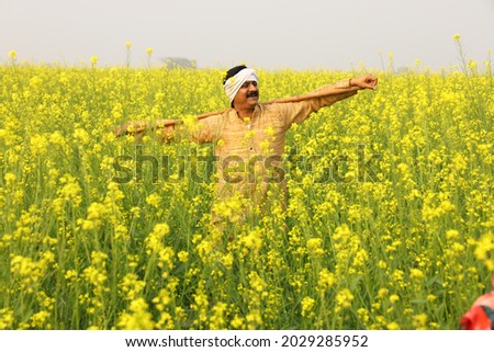 Indian rural happy farmer in village in a mustard field in a green farm yellow flowers. Royalty-Free Stock Photo #2029285952