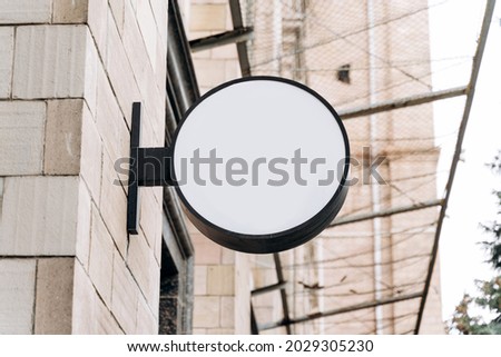 White advertising board on the building. Mock-up of a round street signboard for outdoor advertising on the background of the house