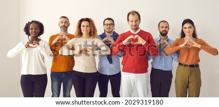 Studio group portrait of thankful youth and senior citizens sending you love, support and gratitude. Team of young and mature people doing heart shape hand gesture isolated on white banner background