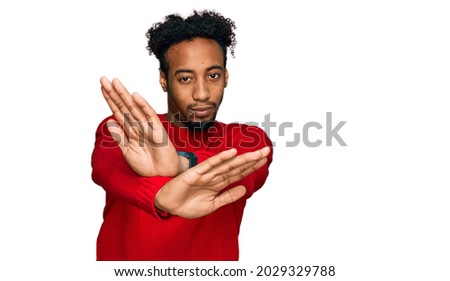 Young african american man with beard wearing casual winter sweater rejection expression crossing arms and palms doing negative sign, angry face 