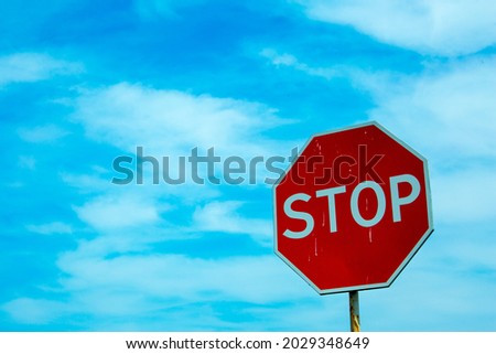 Red traffic stop sign against the blue sky. Sign on the background of the cloudy sky.