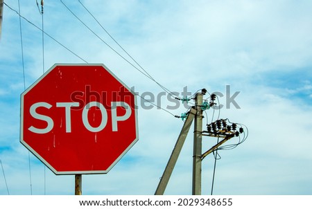 Red traffic stop sign on a background of blue sky and power lines. Sign on the background of the cloudy sky.