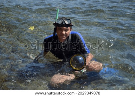 Man in wet suit for underwater activities with dome of action camera for half-underwater photo and video.Marmaris, Turkey