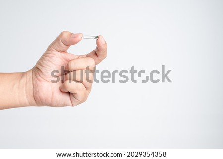Hand holding silver safety pin on white background Royalty-Free Stock Photo #2029354358