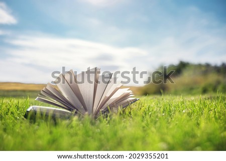 Open book on green grass in a field background concept for reading, relaxing and recreation Royalty-Free Stock Photo #2029355201