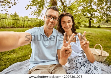 leisure and people concept - happy couple taking selfie and showing peace sign on picnic at summer park