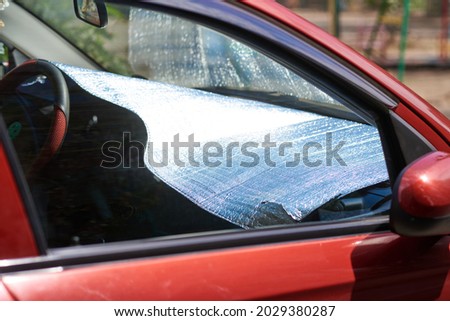 Foil sunscreen shields red car dashboard from sun