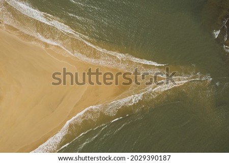 Arial View of island where two oceans meet. triangle shape of sand. waves coming from two sides on island