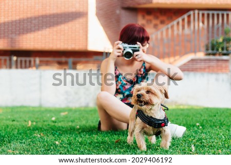 Professional photographer taking pictures of her dog outdoors with her camera