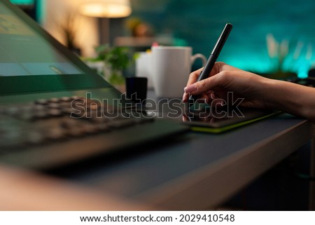 Close up of artistic hand using digital tablet and stylus while retouching image design at professional studio office desk. Woman doing editing work on editor software with modern equipment