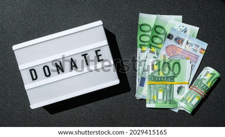Lightbox board with word DONATE in black letters around Euro banknotes. Money, Business, finance, investment, saving. Cash bill. Business budget of wealth and prosperity finance