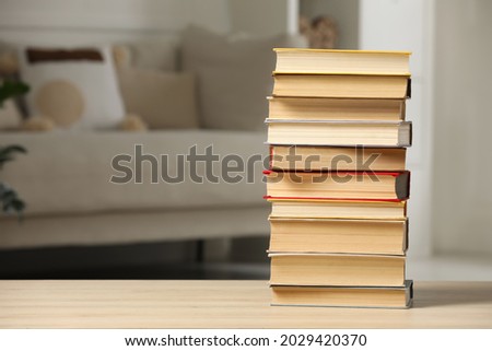 Stack of books on wooden table in living room, space for text. Home library