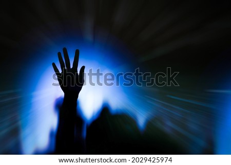 A raised hand with low light in a christian concert. 