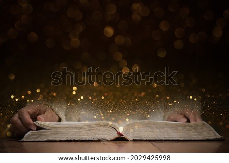 An opened Bible with gold bokeh for background. 
