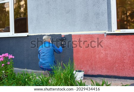 Man painting exterior wall with paint roller. Painter working, man painting wall facade. Worker painting building Royalty-Free Stock Photo #2029434416