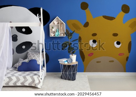 Interior of modern children's room with comfortable bed and paintings of cute animals on wall