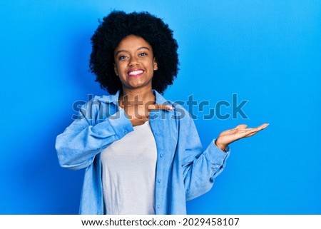 Young african american woman wearing casual clothes amazed and smiling to the camera while presenting with hand and pointing with finger. 