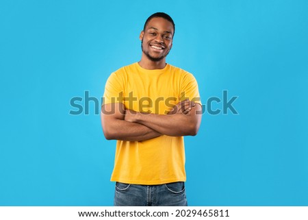 Cheerful African American Guy Smiling To Camera Posing Crossing Hands Standing Over Blue Background. Studio Shot Of Happy Self-Confident Black Millennial Man Expressing Positive Emotions Royalty-Free Stock Photo #2029465811