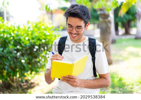 Young student man at outdoors holding a notebook