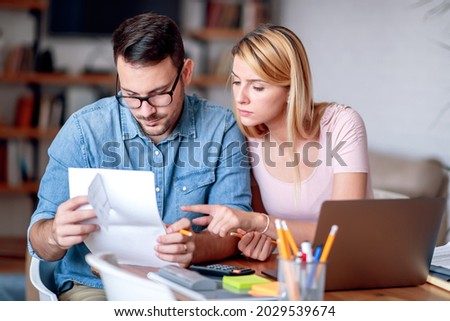 Photo of young couple at home analyzing their finances with laptop.