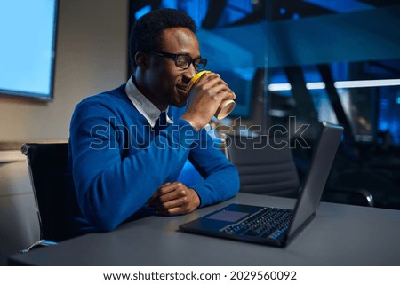 Manager in glasses works on laptop in night offic