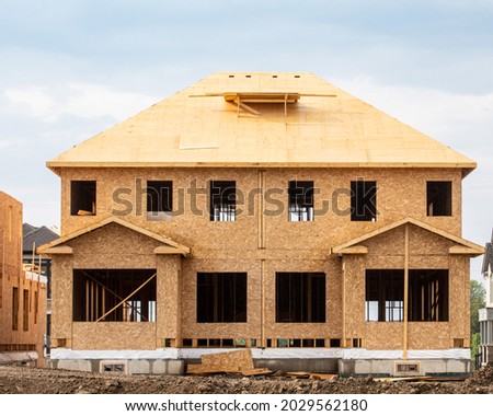 A residential duplex house construction project showing the plywood roof and oriented strand board wall sheathing Royalty-Free Stock Photo #2029562180