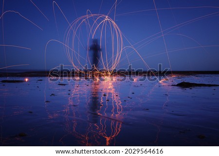 Light Orb on the beach at twilight. Steel wool photography. Long exposure of fire sparks. 
