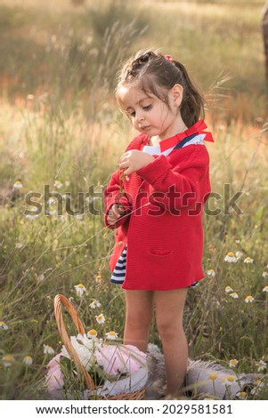Little girl with flower basket in a field with blurred grass in the background