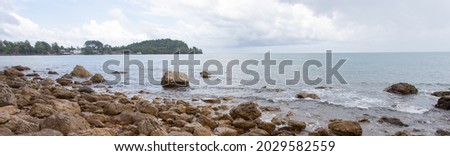 Beach with many rocks, beautiful sea with sky and gray background with light waves, suitable for relaxing, traveling, holiday without crowds.