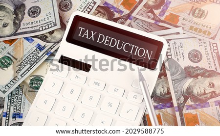 TAX DEDUCTION text on display calculator on dollars background