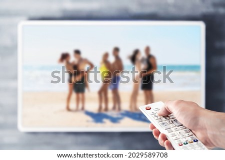 Reality tv show stream on television. Watching series on VOD streaming service. Couples at the beach or island dating, looking for love. Person using remote control. Contest or celebrity entertainment Royalty-Free Stock Photo #2029589708