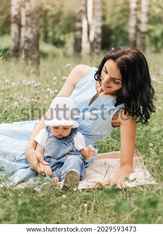 A young mother plays in the park on the grass with her little daughter