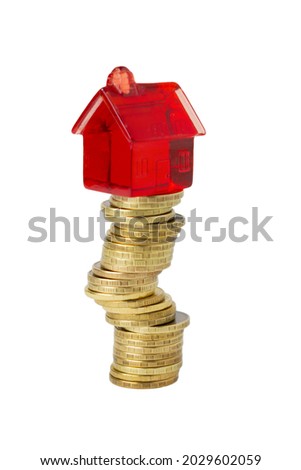 A small red toy house stands on a crooked, wobbly stack of yellow gold coins, isolated on a white background. Economic concept of profit growth, real estate investment, mortgage and capital Royalty-Free Stock Photo #2029602059