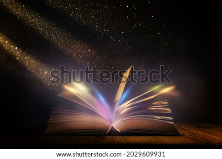 Magical image of open antique book over wooden table with glitter lights Royalty-Free Stock Photo #2029609931